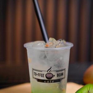 Kiwi soda drink in a plastic cup with fresh kiwi slices