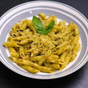 Pesto pasta served in a bowl with basil sauce and herbs